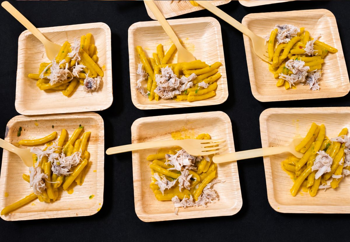 Plates of pasta with crab, plated on palm-leaf dishes at one of the stations