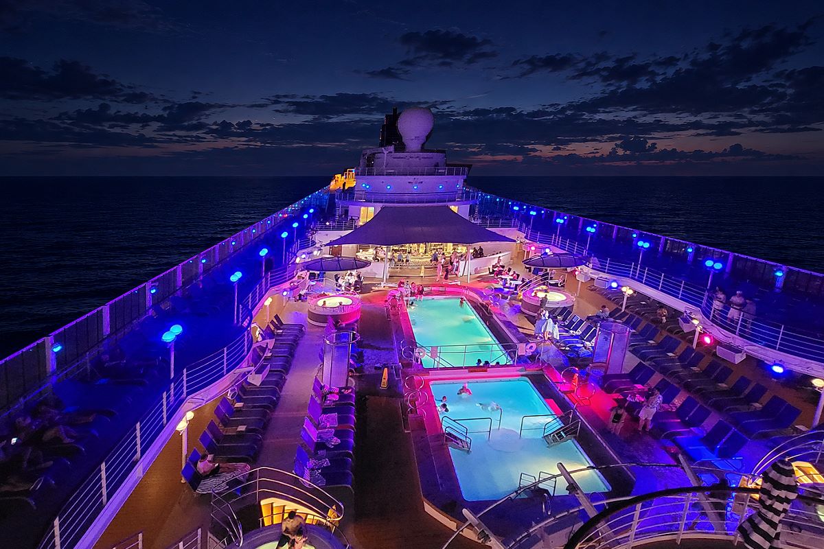 The pool deck of Pride of America lit in blue and pink after sunset