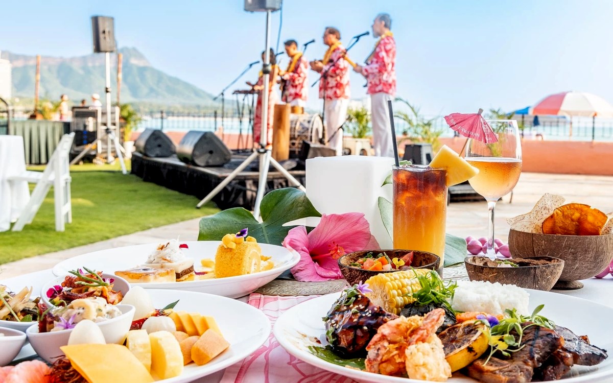 Plated courses and cocktails at Aha Aina, with musicians playing on the lawn stage and Diamond Head beyond