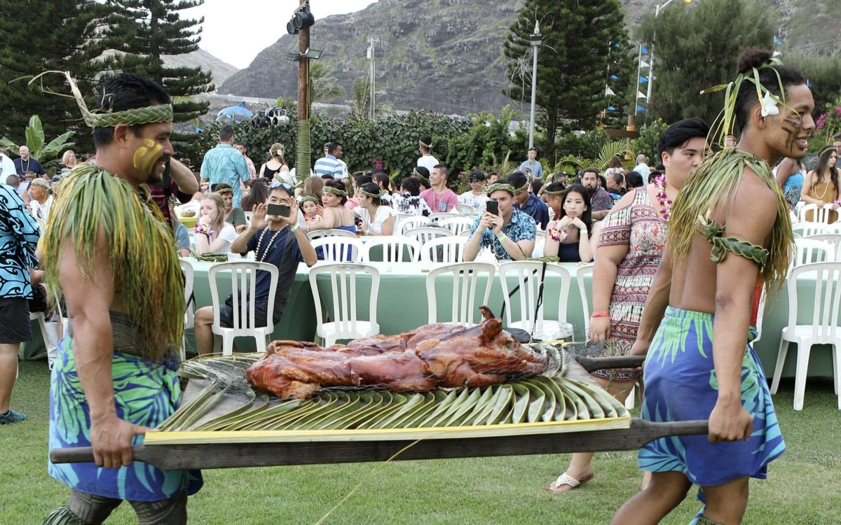 The imu ceremony at Aloha Kai Luau, with the kalua pig carried on ti leaves past the seated guests