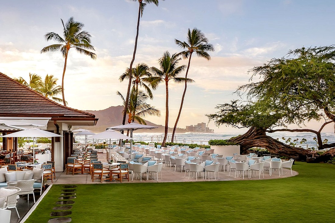 The oceanfront lawn and terrace at House Without A Key, with the old kiawe tree, palms and Diamond Head at sunset
