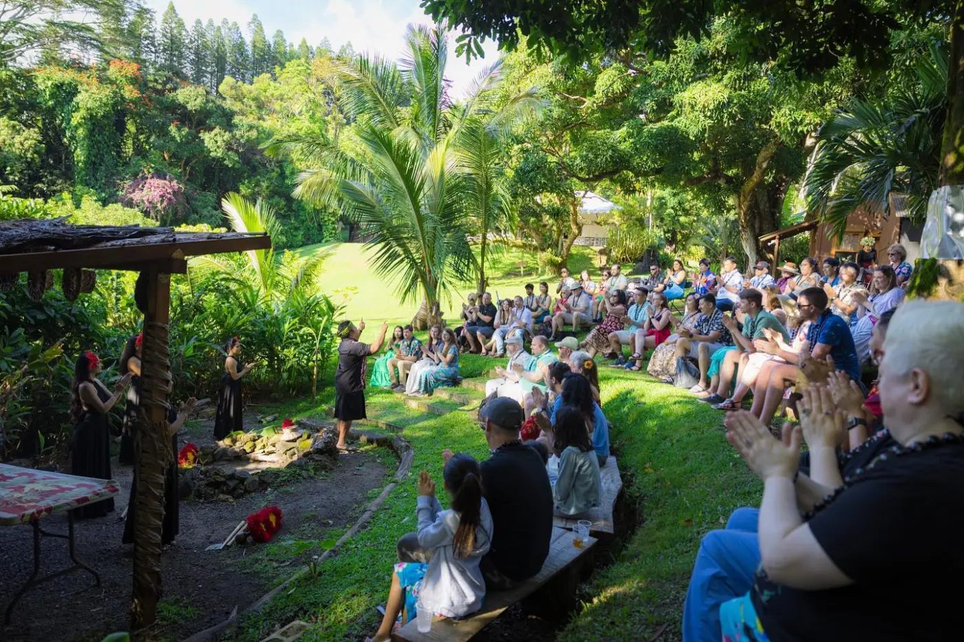 Guests seated on the lawn at Experience Nutridge, surrounded by the trees and gardens of the Tantalus estate