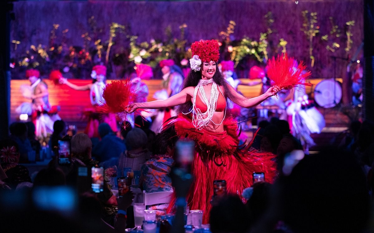 Polynesian dancers in red costumes on the stage at Paina Waikiki Luau