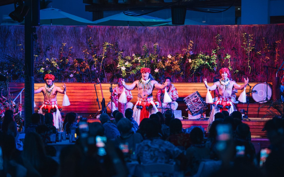 Drummers and dancers under stage lighting at the Paina Waikiki Luau, with the audience close to the stage