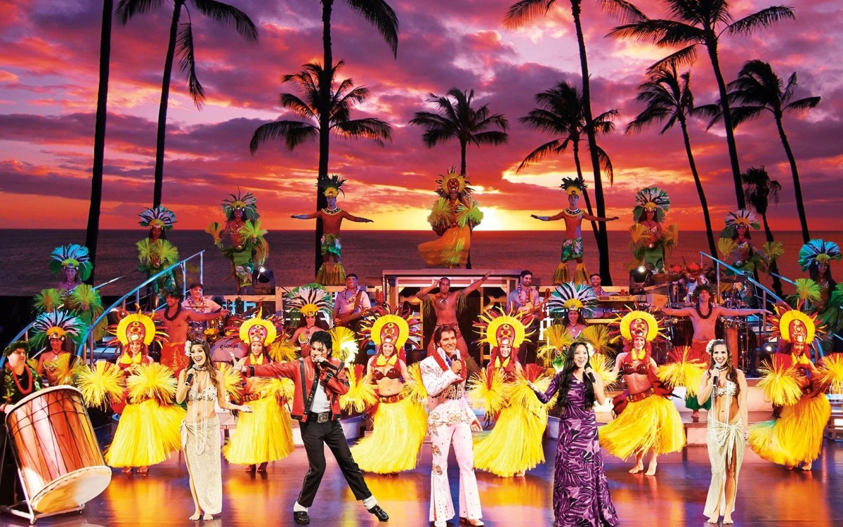 The full Rock-A-Hula cast on stage in bright costumes in front of a painted sunset backdrop